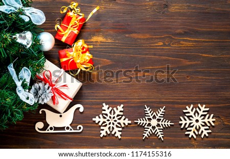 Decorative wooden Christmas snowflakes and sleighs.Holiday wooden background with christmas gift boxes  and fir tree, top view.Flat lay. Copy space.