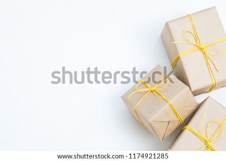 holiday presents wrapped in craft paper and tied with a yellow twine. three festive gift packages on white background with copyspace.