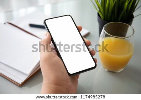 man hand holding phone with isolated screen over table in the office 