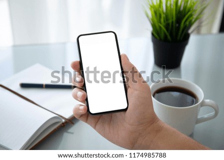 man hand holding phone with isolated screen over table in the office