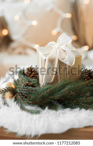 christmas, holidays and decorations concept - christmas gift and fir wreath with cones and balls at home on sheepskin
