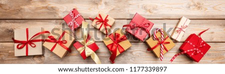 Christmas gift boxes with red ribbons on wooden background, banner, top view