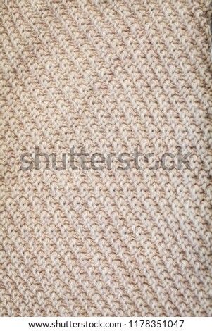 Background texture of beige pattern knitted fabric made of cotton or wool top view.