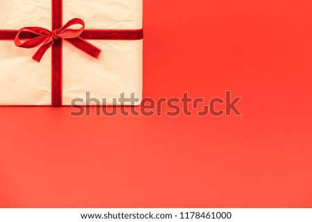 Christmas gift box on red background. White recycled / reused wrapping paper with red ribbon. Empty blank copy space for text.