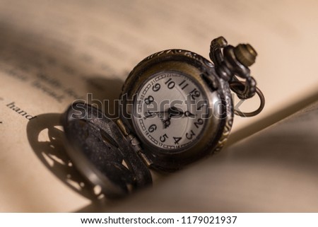 A pocket watch on the book’s page