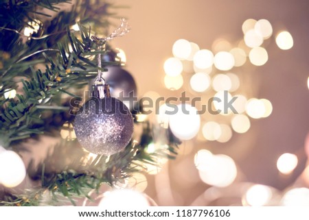 Closeup of silver bauble hanging from a decorated Christmas tree with bokeh, copy space, Xmas holiday background.