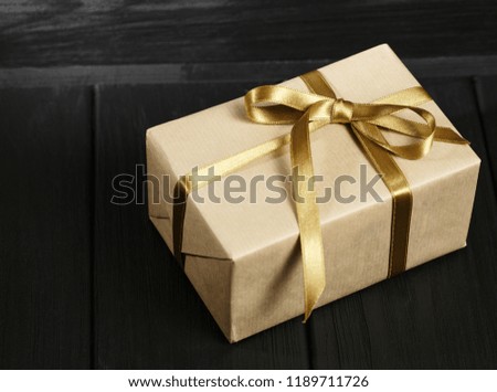 Gift box with golden ribbon on black wooden background top view. Discount gift for sale day. Flat lay with copy space. Holiday concept.