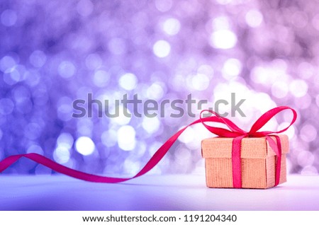 Christmas and new year gift box with red long ribbon and shiny bokeh background.
