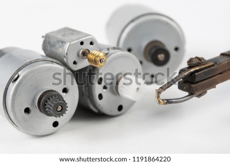 Repair of a small electric motor. Simple soldering work in the electronics workshop. White background.
