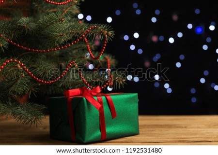 Green gift with red ribbon, Christmas tree and decorations on the table. New year.