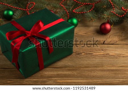 Green gift with red ribbon, Christmas tree and decorations on the table. New year.