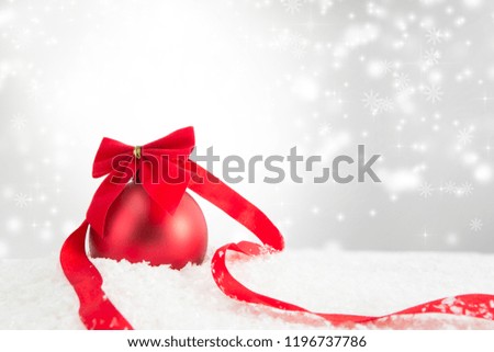 Red Christmas ball on a white snow surface over gray background.