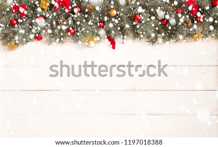 Christmas firtree with christmas decorations and lights on white wooden background with snow.