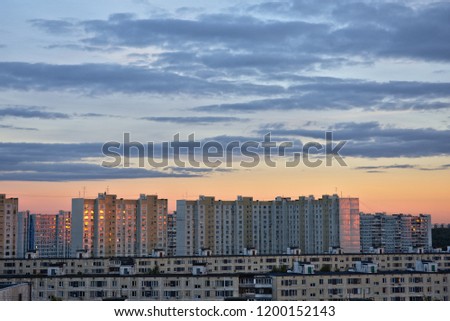 A view of Moscow's outskirts during a sunset with clouds, red reflection and lots of windows