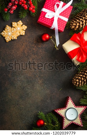 Christmas decorations on dark stone background. Fir tree branch, present box, candleand red balls. Top view with copy space.
