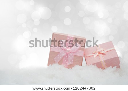 Pink gift boxes on the snowfall with copy space for season greeting Merry Christmas or Happy New Year.