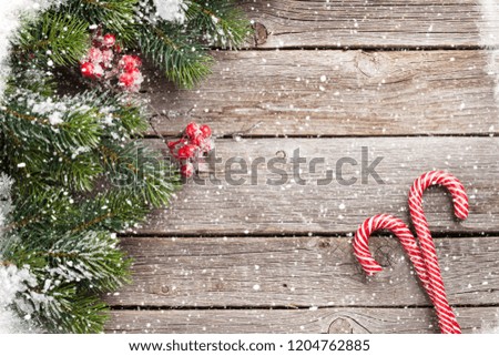 Christmas candy cane and snow fir tree on wooden table. Top view with space for your greetings