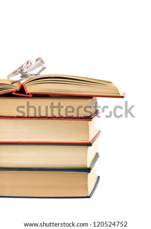 Open book and glasses lying on a pile of books on a white background