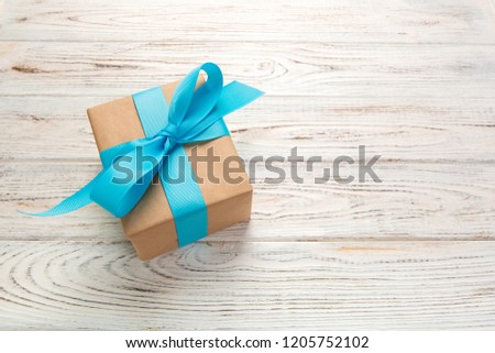 Beautiful gift box with a blue bow on the white wooden table. top view.