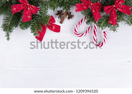 Christmas composition. Christmas decoration, ribbons, candy canes, fir branches on wooden white background. Flat lay, top view, copy space, background.
