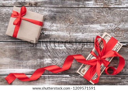 Christmas background of old wood, money embellished with red slack and gift. Top view.