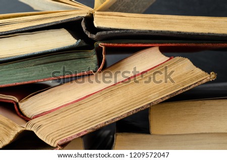 Close up of a pile of old text books, opened as if study in progress, stacked untidily with blackboard background. 