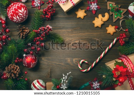 Frame with  fir branches, cookies and Christmas decorations on dark wooden background.  Top view.