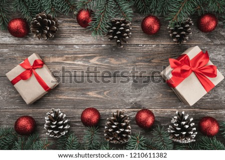 Old wood background with fir branches adorned with baubles and cones. Space for text. Christmas card. Top view. Xmas gifts.