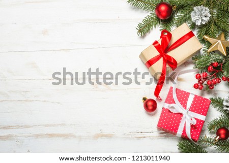 Christmas background with fir tree, present box and decorations on white wooden background. Top view with copy space.
