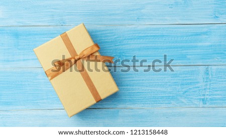 Gold gift box on a blue wooden table.