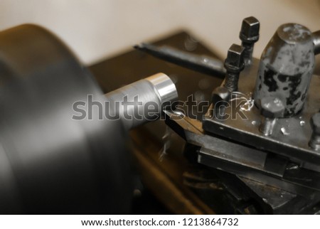 turning a rotating workpiece on a old manual metalworking lathe, focus on the tip of the tool bit
