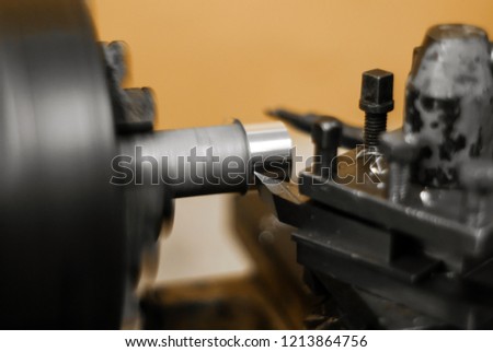 turning a rotating workpiece on a old manual metalworking lathe, focus on the tip of the tool bit