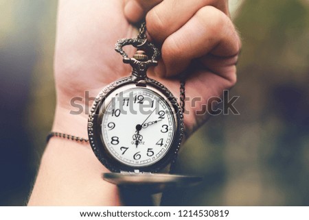 Abstract human hand holding ancient pocket watch and nature background. Time of life concept.