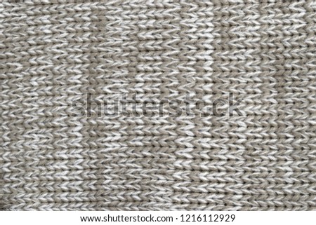 White and khaki melange yarn fabric knitted texture background. Closeup view.