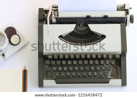 Vintage typewriter and a cup of coffee on white table at top view.