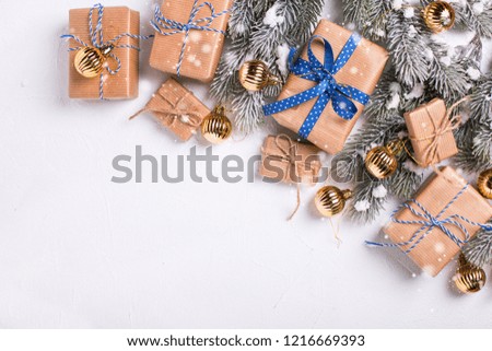 Wrapped christmas presents, golden balls  and fur tree branches  on  white textured  background. Selective focus. Top view. Place for text.