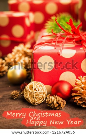 Christmas and New Year Day festive decoration, toys, presents wrapped in red paper with golden circles on wood background with text Merry Christmas and Happy New Year on red. 