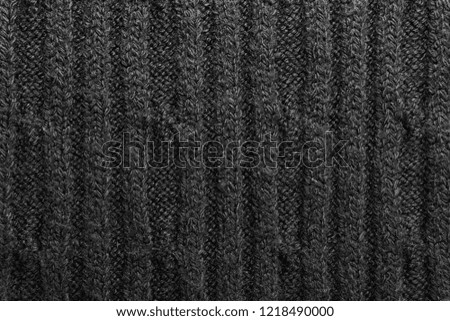 Texture of a black knitted sweater closeup. dark knitted wool material background