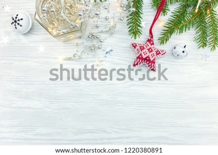 christmas ornaments with lights garland, stars and fir tree branch on wooden background