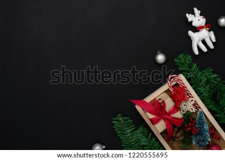 Table top view of Merry Christmas decorations & Happy new year ornaments concept.Flat lay essential objects the reindeer & gift box on modern rustic wood black background at home studio office desk.