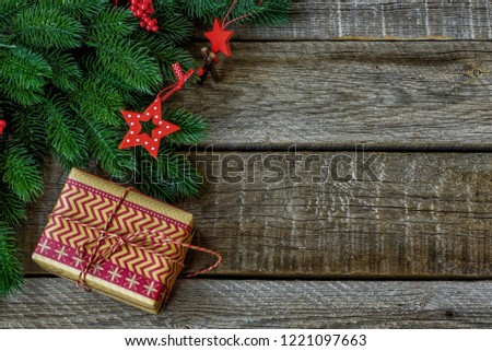 Christmas background with decorations and gift box on dark wooden board. Christmas gift, stars, fir branches. Toned image with copy space.