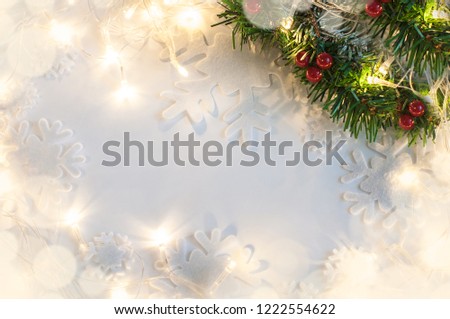 Christmas tree branch in top right corner on a white background with holiday garland lights.