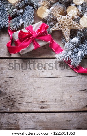  Christmas present in wrapped box,  star and branches fur tree on  vintage wooden background. Decorative christmas composition. Selective focus. Place for text. Vertical image.