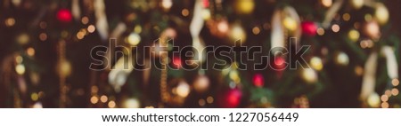 Christmas blurred background. Dressed up Christmas tree with ribbons and gold and red balls.