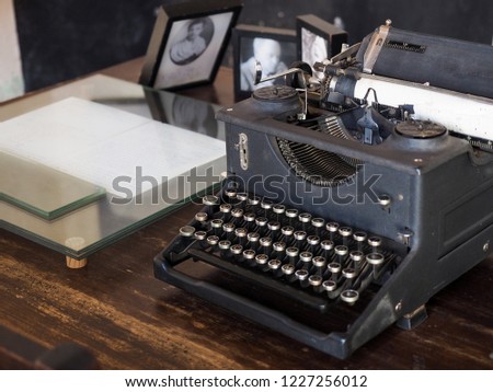 Side angle shot of old typewriter as foreground and vintage work station or work table in the background