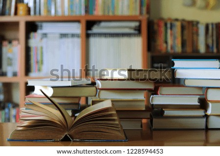 Close-up of old book opened on library table many books stacked as backgrounds selective focus and shallow depth of field