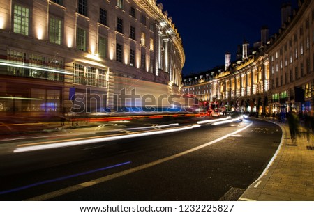 night scene of London city United Kingdom with the moving red buses and cars - long exposure photography
