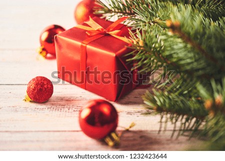 Christmas background. Fir tree and a lot of christmas red baubles and gift box over white wooden board