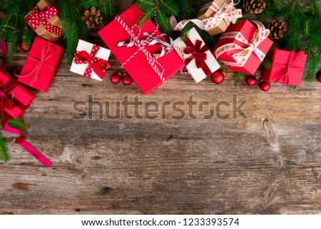 Christmas gift giving concept - christmas presents in red and white boxes on textured wooden table, flat lay row with copy space
