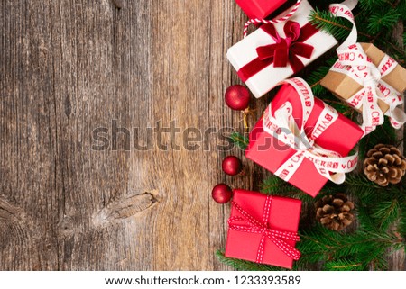 Christmas gift giving concept - christmas presents in red and white boxes on textured wooden table, top view row with copy space